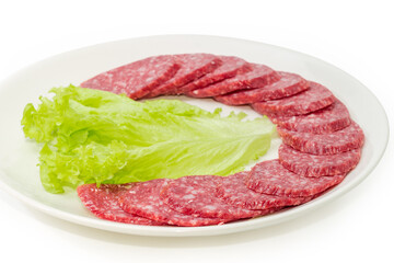 Sliced salami with lettuce leaf on dish close-up