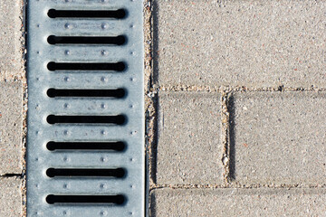 Manhole on concrete drain system cover. Urban sewer background. Metal drain cover texture. Pavement water drainage system. Vertical silver color metal grid.
