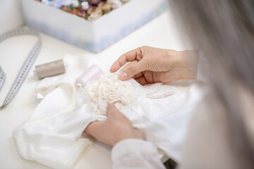 Fototapeta na wymiar Female hands sewing white textiles at table