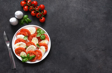 Caprese is a tomato and mozzarella appetizer. Traditional Italian salad on a concrete background with space for text.