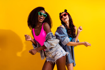 Obraz premium Photo of two young girl happy positive smile have fun dance wear sunglass isolated over yellow color background