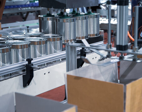 Automation robot lifting food can into carton in production line. Food industry.