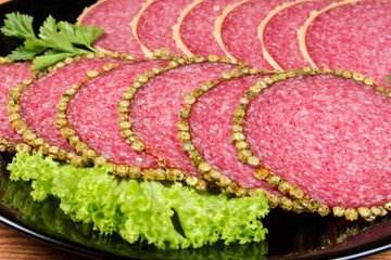 Slices of salami in peppercorns and parmesan crusts close-up