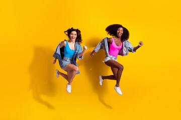 Fototapeta na wymiar Full size photo brunette happy ladies jump up run sale hurry wear summer clothes girlfriends isolated on yellow color background