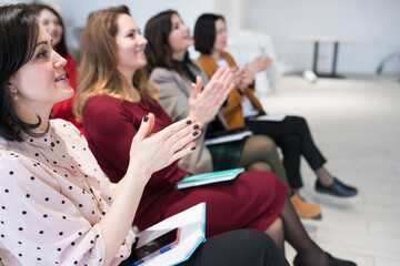 Group of people clapping their hands during seminar. Women applauding speaker at group session, sitting in audience at training meeting.