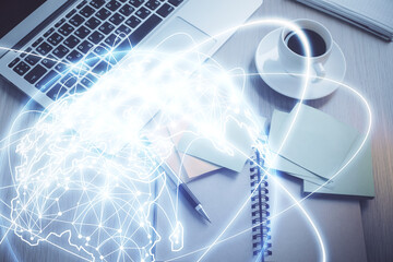 Business theme hologram drawings over computer on the desktop background. Top view. Multi exposure....