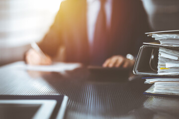 Binders with papers are waiting to be processed by unknown man accountant in blue blazer staying at home during covid pandemic. Taxes and audit concept