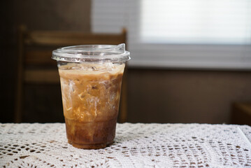 Iced black coffee and cream. A plastic cup of black coffee, espresso shot mixed with milk cream on table at coffee cafe.