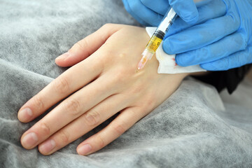 A plastic surgeon doctor does an injection of a beauty injection into the hands of an elderly...