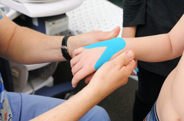 Child with hand injury during kinesio taping therapy. Kinesiology, physical therapy, rehabilitation banner.