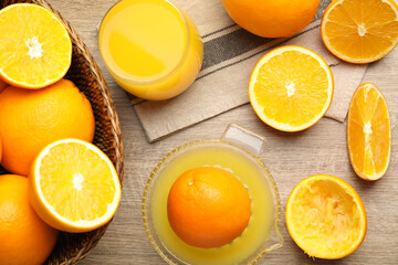Fototapeta na wymiar Squeezer, fresh oranges and juice on wooden table, flat lay
