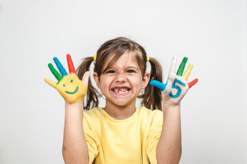 Happy toothless little girl with the five number painted on the hand laughing and having fun -...