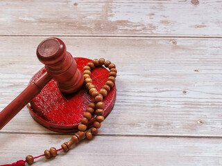 Selective focus gavel with prayer beads isolated on wooden background. Islamic law concept.