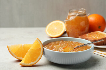 Fototapeta na wymiar Delicious orange marmalade in bowl on light grey table. Space for text
