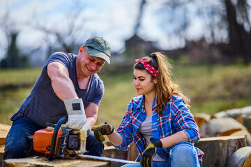 Naklejka na ściany i meble Lumberjack teaches his apprentice how to use the chainsaw