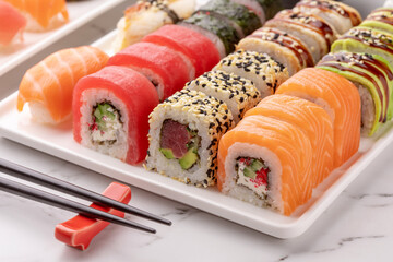 Sushi rolls set on a white square dish and chopsticks on a white stone background. Traditional Japanese food. Asian food