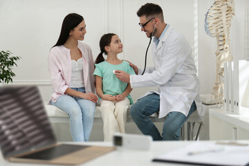 Mother with daughter visiting pediatrician in hospital. Doctor examining little girl