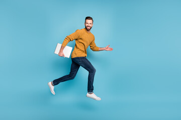 Naklejka na ściany i meble Full length body size view of nice cheerful skilled successful guy jumping running carrying laptop isolated on bright blue color background