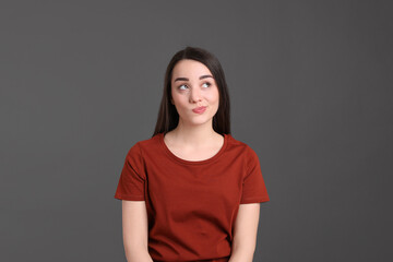 Obraz premium Portrait of emotional young woman on dark grey background. Personality concept