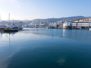 Fototapeta na wymiar Genoa, Italy- April 01, 2021: Panoramic view of the waterfront and the old italian sea port in Genova by spring with blue sky and clear water.