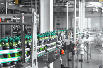 Industrial beverage factory interior with automated computerized conveyor line or belt and plastic bottles with organic juice.