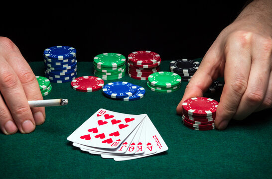 Hands of a gambler closeup and chips on green table in a poker club. A player places a bet on winning poker