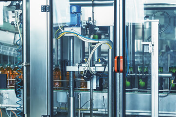 Automatic machine for dressing packaging for plastic bottles with drink in factory, industrial production of juices and other drinks.