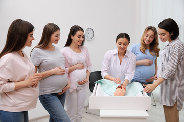 Fototapeta premium Pregnant women learning how to swaddle baby at courses for expectant mothers indoors