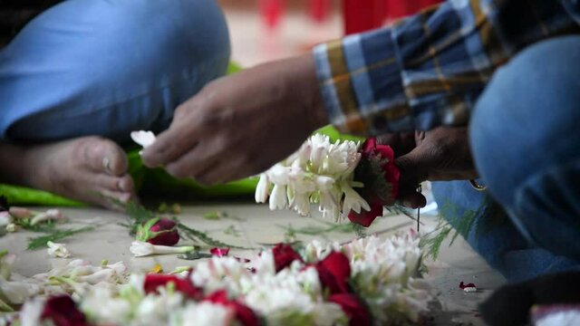 Two boys are making garlands of different flowers