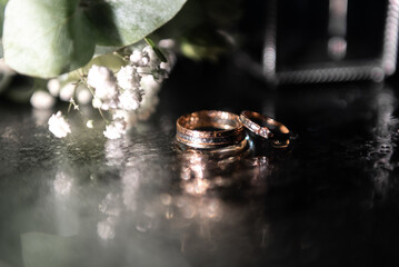 Wedding rings on a dark background. The bride's bouquet and glasses.