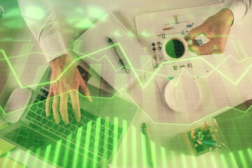 Multi exposure of man's hands typing over computer keyboard and forex graph hologram drawing. Top view. Financial markets concept.