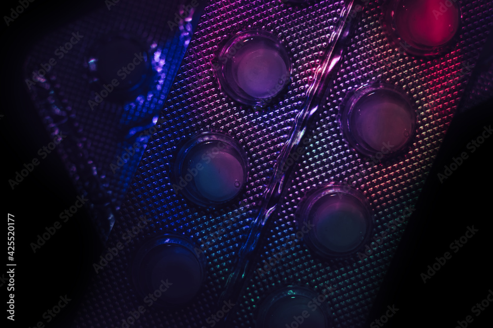 Poster pills or drugs in a package under neon light on a dark background pattern for design..
