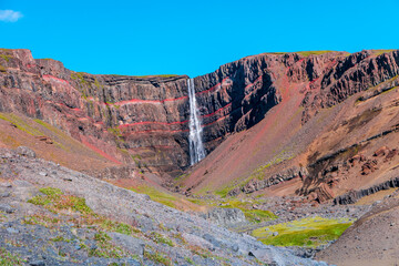 Beautiful and tall Icelandic waterfall Hengifoss, Iceland, at sunny day and blue sky, summer.