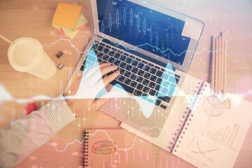 Double exposure of man's hands typing over computer keyboard and forex graph hologram drawing. Top view. Financial markets concept.