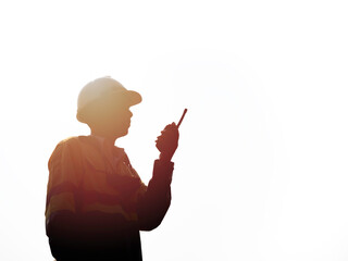 Engineering man using walkie-talkie on sunset background. - obrazy, fototapety, plakaty