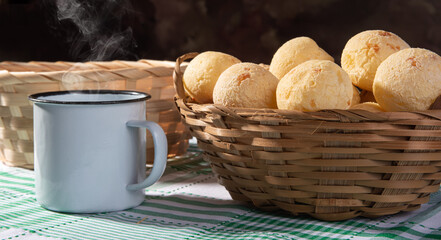 Cheese bread, straw basket full of cheese bread and a white cup on a checkered tablecloth, selective focus.