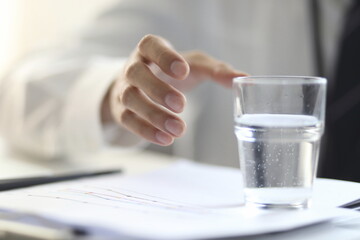 Cropped image of businessman with glass of water on desk
