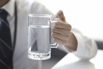 Close up of businessman holding glass of water