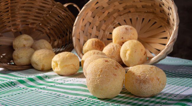 Cheese bread, fallen straw basket with cheese bread on a checkered tablecloth, selective focus.