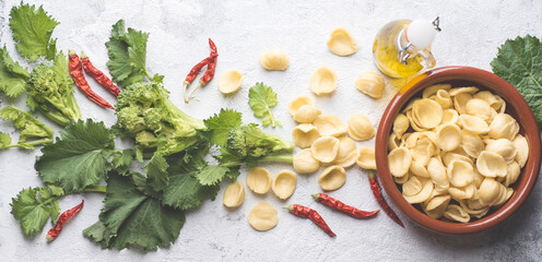 Italian handmade pasta Orecchiette with turnip leaves and tops or cima di rapa with chili pepper, olive oil on white table. Recipes and ingredients of southern Italy, Puglia. Internet banner