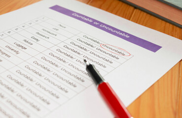 Naklejka premium English grammar test sheet on wooden table