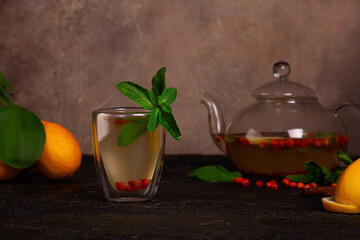 Hot tea with lemon, sea buckthorn, cinnamon and mint. Tea in a glass teapot. Selective focus.