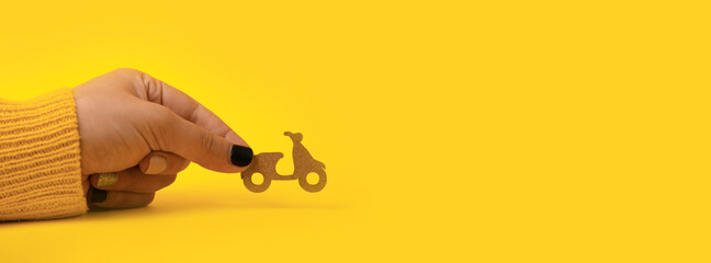 delivery wooden scooter in hand over yellow background, panoramic mock-up