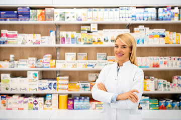 Portrait of smiling female caucasian pharmacist standing in drug store with arms crossed.