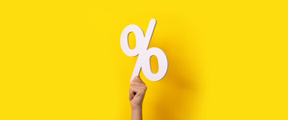 hand holding percentage sign over yellow background - obrazy, fototapety, plakaty
