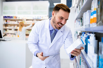 Pharmacist working in drug store and holding medicine.