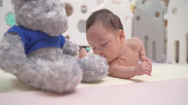 3 months. cute asian baby infant playing on pastel play mat. lovely kid learning to crawl at home. soft mat in playpen protection in baby playground and plastic fence.