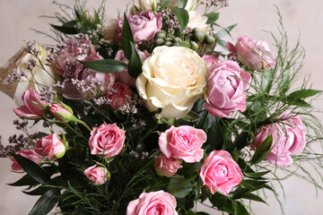 Beautiful bouquet with roses on beige background, closeup