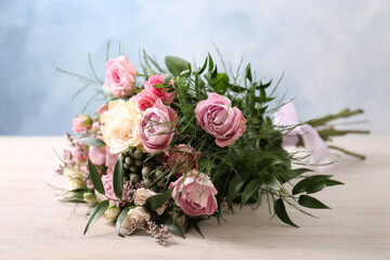 Beautiful bouquet with roses on light wooden table