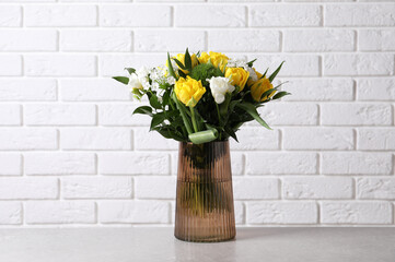 Beautiful bouquet with peony tulips on grey table near white brick wall